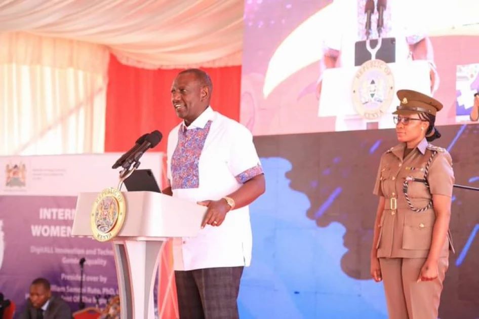 ADC Damaris Agnetta standing behind President William Ruto while making his speech during the International Women's Day 2023 celebrations.